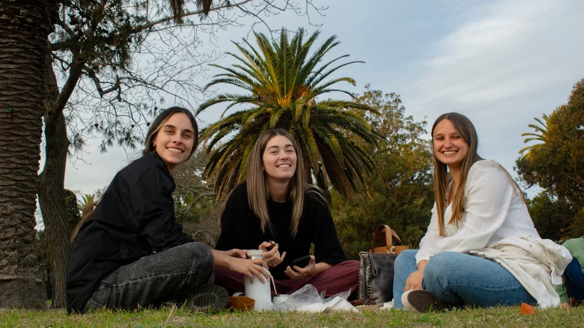 Three young adults enjoy a picnic outdoors, creating a joyful and relaxed atmosphere.
