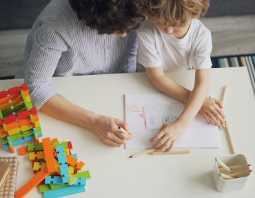 a woman and a child sitting at a table working on a project